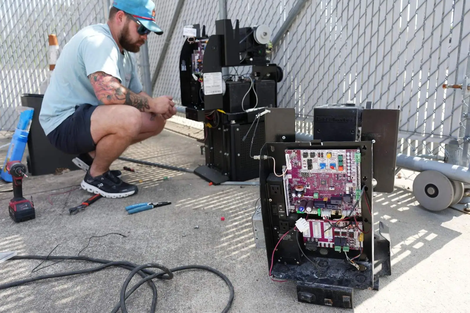 Technician working on an opened gate operator with the control board and wiring exposed