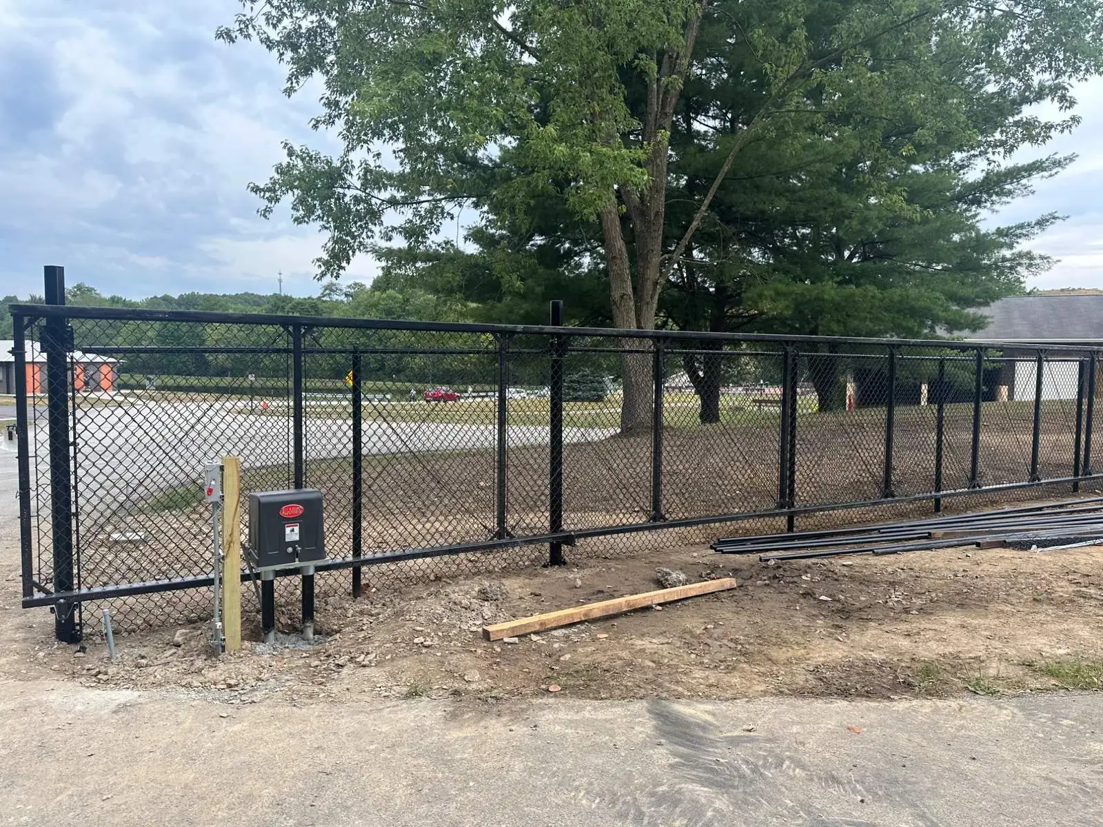 Black steel slide gate on a chain-link perimeter.